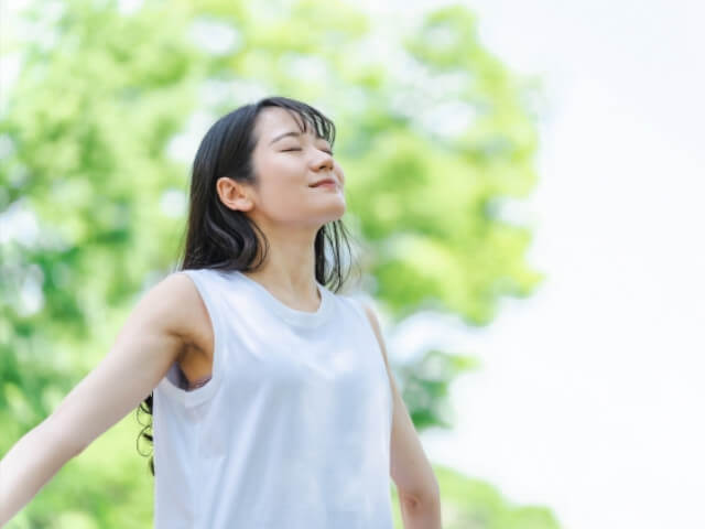 公園で深呼吸をしている女性をイメージした画像です。